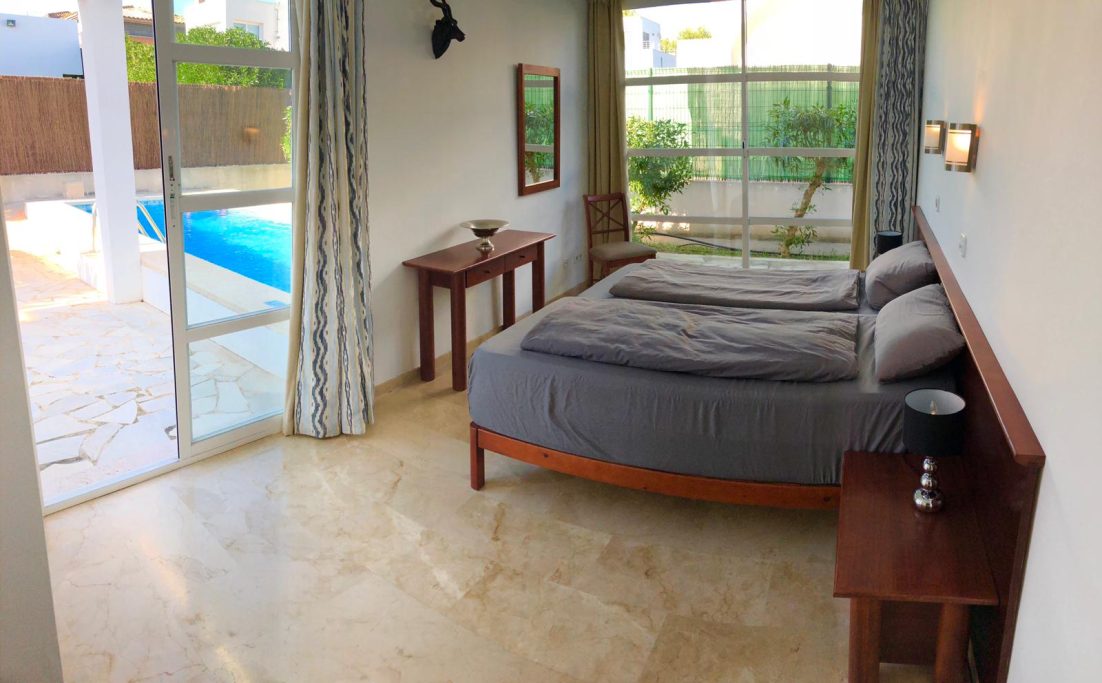 2. Schlafzimmer Geräumiges Schlafzimmer mit zwei Betten, Blick auf einen Außenpool und große Fenster.