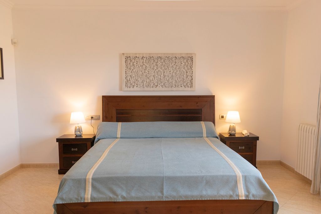 Master Schlafzimmer Schlafzimmer mit einem Bett, Nachttischen und zwei Lampen in einem hellen Raum.